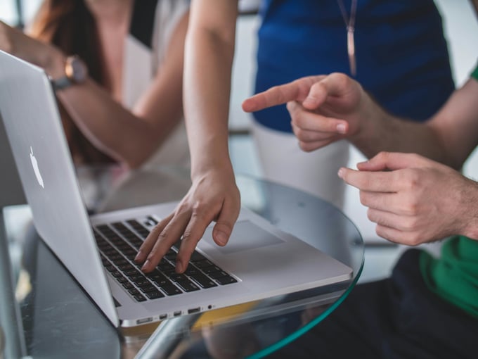 hands around a laptop discussing a problem